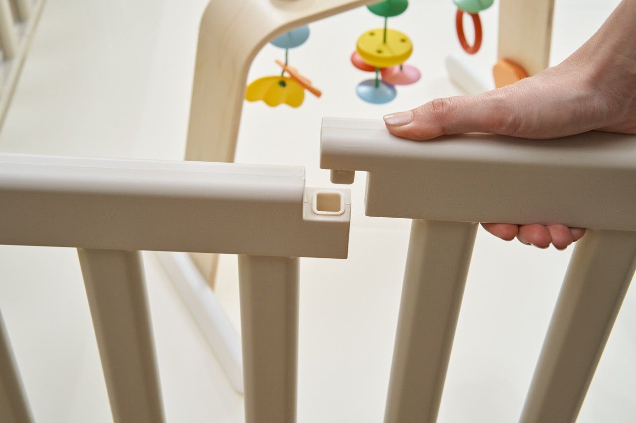 Close-up of hand assembling white baby playpen panel connection