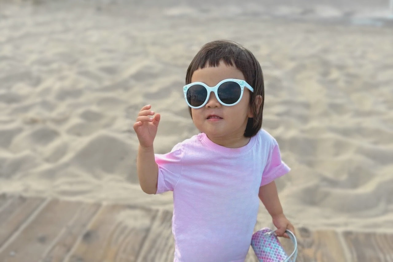 Founder’s daughter wearing sunglasses while playing on a sandy beach