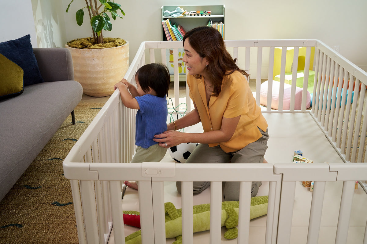 Parent playing with child inside premium baby playpen on cushioned play mat