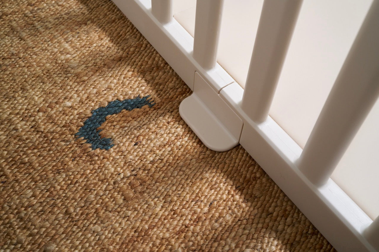 Close-up of safety foot and locking mechanism on white baby playpen panel