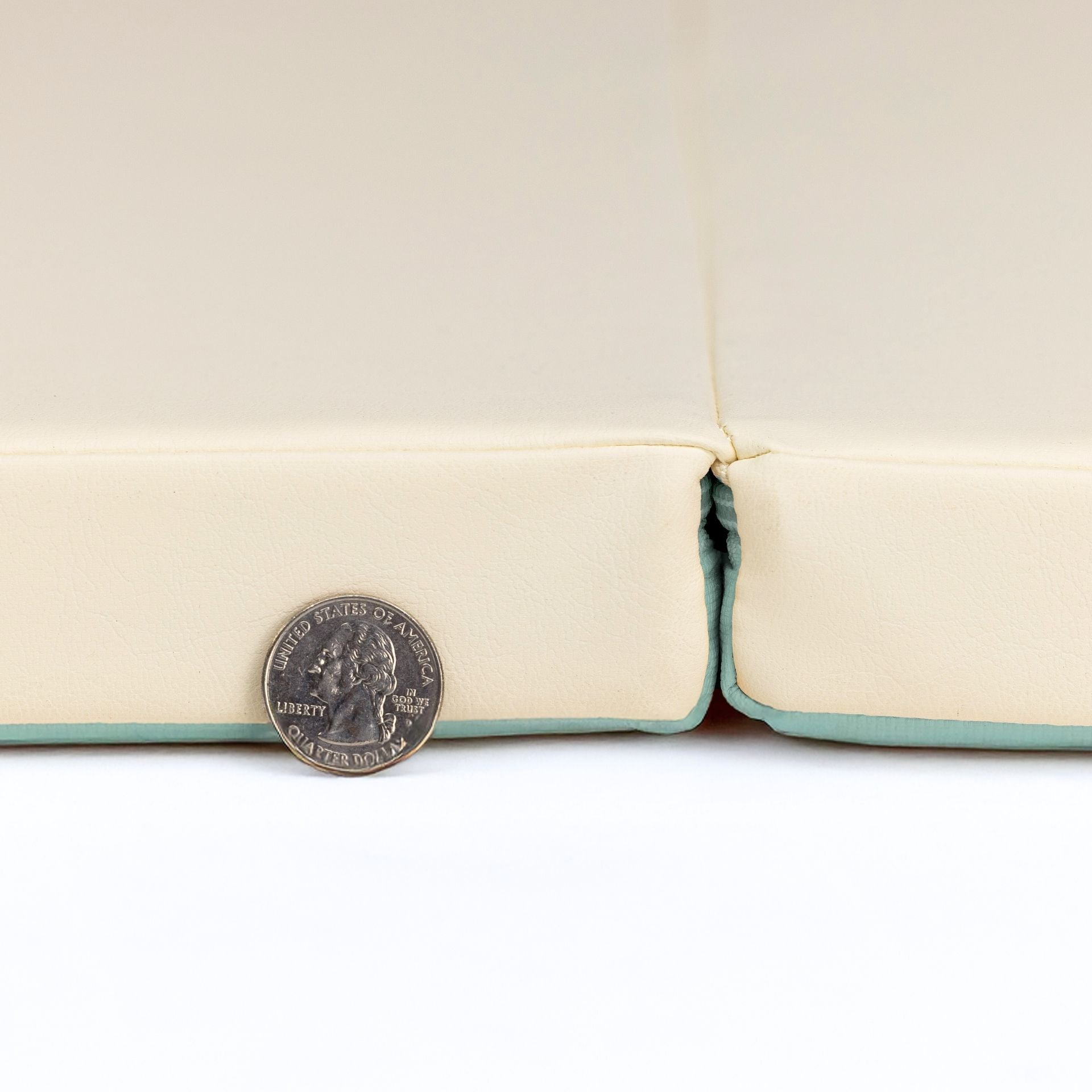 Close-up of taupe cushioned non-toxic baby play mat showing thickness with coin for size comparison